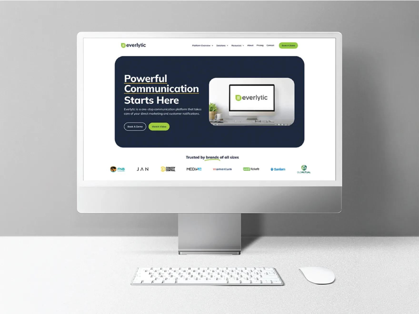 Everlytic homepage on a desktop monitor with the headline Powerful Communication Starts Here, a product screenshot and a row of client logos.